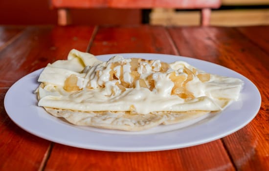 Plate of delicious Quesillo with pickled onion served on the table, Traditional quesillo plate with pickled onion and cream. Concept of typical Nicaraguan foods