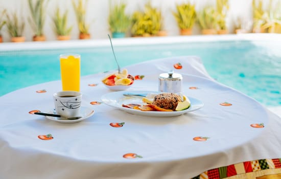 Breakfast served on the table with a swimming pool in the background. fruit salad. Traditional breakfast served at the table near a swimming pool