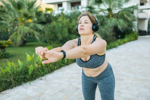 Young pretty smiling plus size woman in sporty top and leggings doing sport in summer outdoor