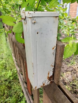 Old gray empty mailbox on a wooden fence close up.