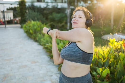 Young pretty smiling plus size woman in sporty top and leggings doing sport in summer outdoor