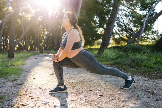 Young pretty smiling plus size woman in sporty top and leggings doing sport in summer outdoor