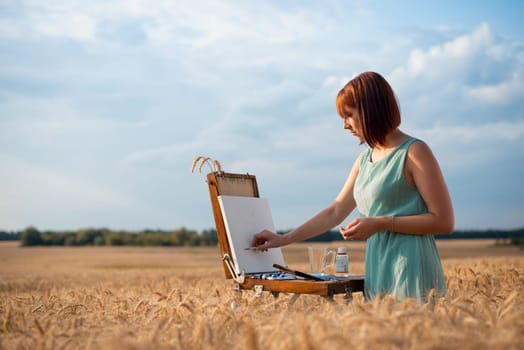 Young girl painter starting a painting in the fields