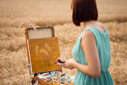 Girl painting three spikelets in the field of ripe grain, enjoying the nature and beauty around