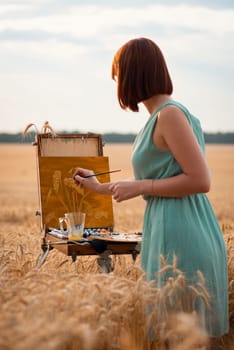 Girl painter in light dress meticulously painting all the small details of spikelets in the field