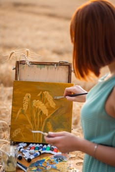 Back view of a girl painter depicting wheat spikelets on canvas