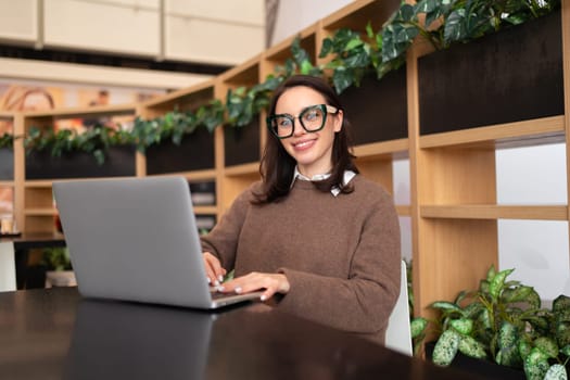 Woman Wearing Glasses using Laptop. Smiling businesswoman in eyeglasses and casual clothes working with laptop computer watching screen. Elegant business female medium shoot