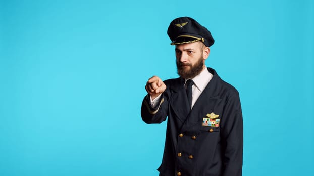 Plane captain in aviation uniform pointing at camera and choosing, saying i want you for commercial flights aircrew. Young male pilot flying airplane and acting confident, feeling successful.