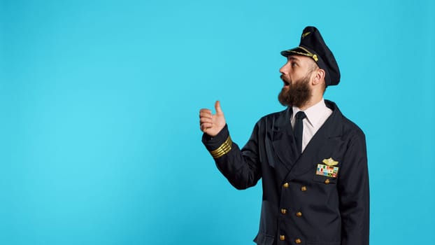Airline pilot pointing to left or right sides on camera, indicating direction sideways and working in flying industry. Young man dressed as captain having professional occupation, aside.