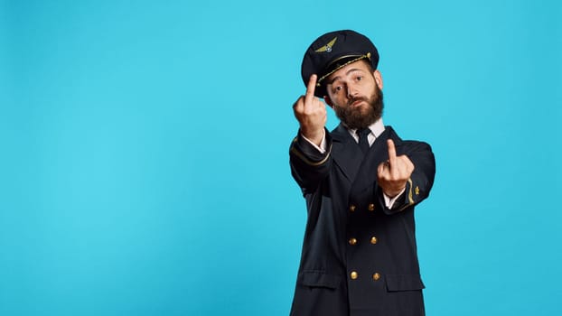 Caucasian airline captain showing middle fingers on camera, advertising negative rude symbol. Professional flying pilot acting aggressive and furious with obscene gesture, disagreement.