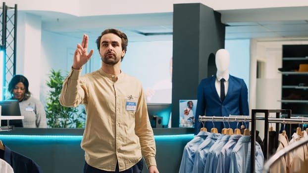 Clothing store assistant checking stock on hologram, working in shopping center with artificial intelligence and augmented reality. Young employee using holographic images, small business concept.