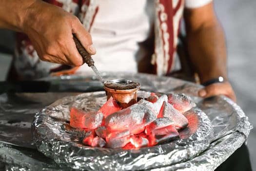 Cooking of Turkish coffee by classical method in turk on coals, men's hands close-up