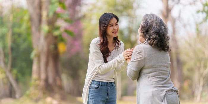 Close up of Adult daughter holding her elderly mother hand with love and walk together.