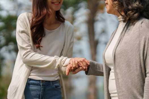 Close up of Adult daughter holding her elderly mother hand with love and walk together.