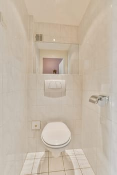 a white toilet in a bathroom with tile flooring and wall mounted mirror above the toilet is an image of a woman's reflection