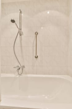 a white bathtub in the corner of a bathroom with a shower head and hand rail attached to the wall