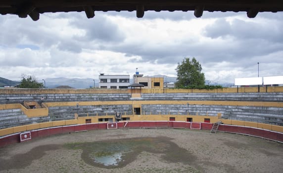 empty and abandoned bullring on a cloudy day with a puddle of water in the middle of the bullring of ecuador