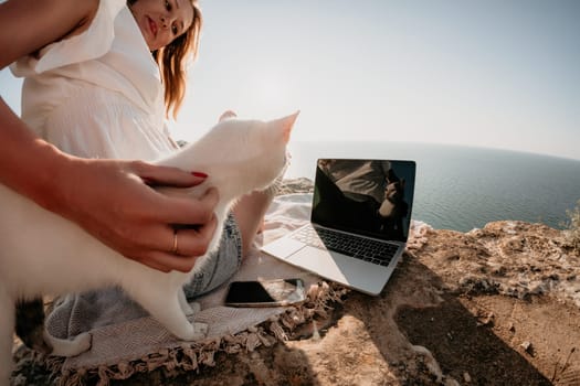 Woman sea laptop. Business woman in yellow hat working on laptop by sea. Close up on hands of pretty lady typing on computer outdoors summer day. Freelance, digital nomad, travel and holidays concept.