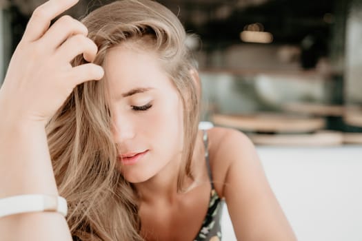 Happy woman portrait in cafe. Boho chic fashion style. Outdoor photo of young happy woman with long hair, sunny weather outdoors sitting in modern cafe