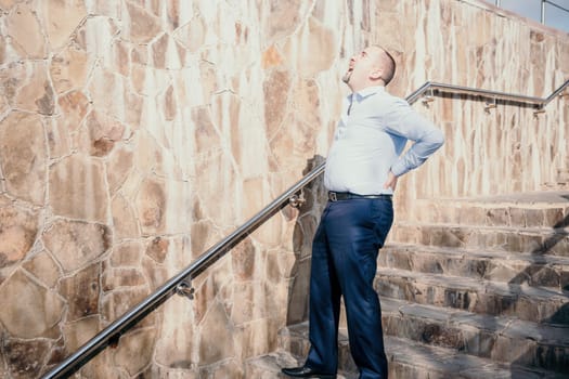 Portrait of a senior professional man in a suit with various problems. A middle-aged businessman with a briefcase descends the stairs.