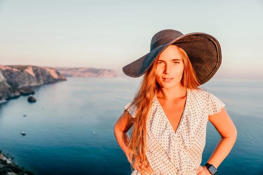 Portrait of happy young woman wearing summer black hat with large brim at beach on sunset. Closeup face of attractive girl with black straw hat. Happy young woman smiling and looking at camera at sea