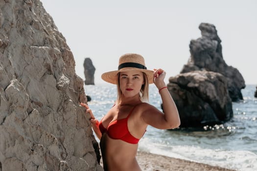Woman travel sea. Young Happy woman in a long red dress posing on a beach near the sea on background of volcanic rocks, like in Iceland, sharing travel adventure journey