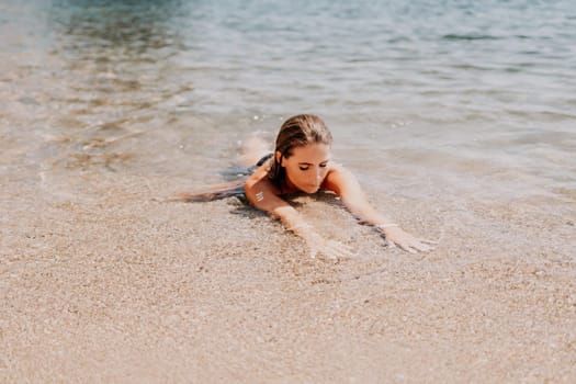 Woman travel sea. Young Happy woman in a long red dress posing on a beach near the sea on background of volcanic rocks, like in Iceland, sharing travel adventure journey