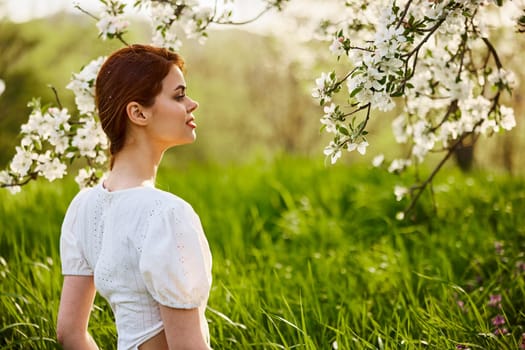 portrait of a beautiful woman looking at the flowers of an apple tree. High quality photo