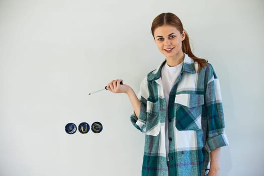 happy, smiling woman stands with a screwdriver and fixes sockets on a light wall. High quality photo