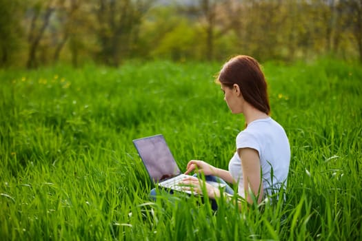 Business woman relaxing in green grass field outdoor under sun. Bright sunny day. High quality photo