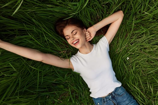 joyful, happy, carefree woman lies on the grass with her arms outstretched. High quality photo