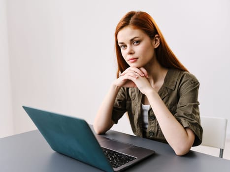 pensive redhead woman sitting at laptop while working in office. High quality photo
