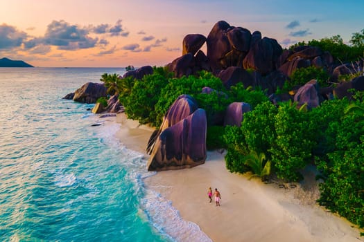 Anse Source d'Argent beach, La Digue Island, Seyshelles, Drone aerial view of La Digue Seychelles bird eye view.of tropical Island, couple men and woman walking at the beach during sunset at a luxury vacation