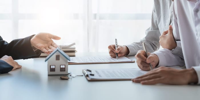 Happy couple signing a contract with real estate agent. renters tenants sign mortgage loan investment agreement or rental insurance contract meeting realtor lender landlord making real estate sale purchase deal.