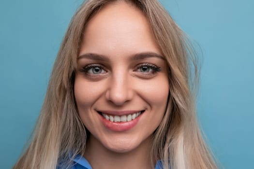 beautiful young woman in a blue shirt smiling cheerfully on a blue background.