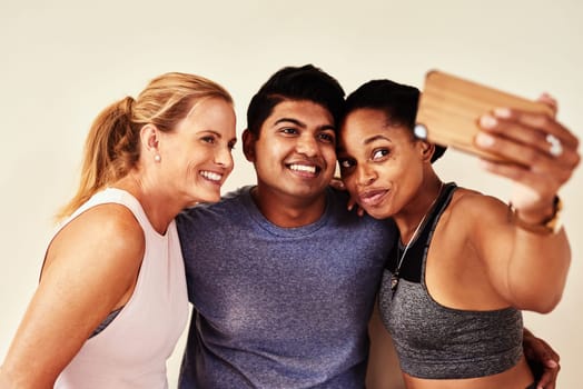 Whats a workout without awesome friends. a group of young men and women taking selfies in yoga class