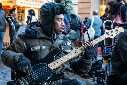London, United Kingdom - November 25th, 2006: Unknown busker plays bass guitar and signs at Covent Garden. Street performers are performing often in this area, as it's popular tourist spot.