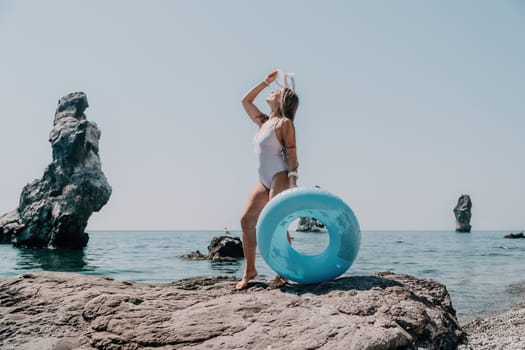 Woman summer sea. Happy woman swimming with inflatable donut on the beach in summer sunny day, surrounded by volcanic mountains. Summer vacation concept