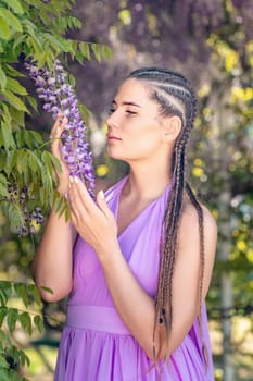 Woman wisteria lilac dress. Thoughtful happy mature woman in purple dress surrounded by chinese wisteria.