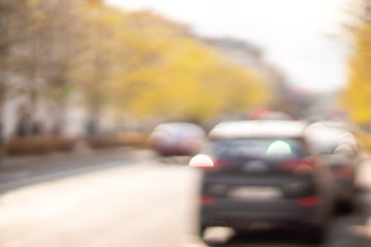 Autumn season bokeh background. Abstract city blur along the road with cars