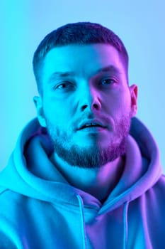 handsome bearded man in sweatshirt on blue background. Neon lighting