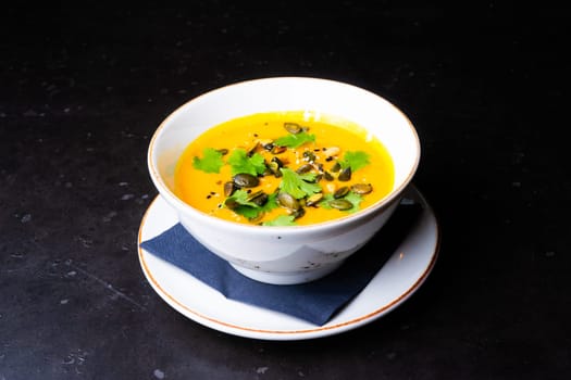 Pumpkin cream soup with parsley on a gray stone and wooden background. Top view, copy space