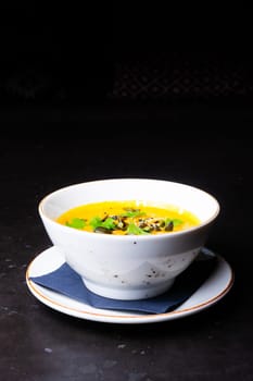 Pumpkin cream soup with parsley on a gray stone and wooden background. Top view, copy space