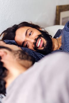 smiling happy man relaxed in bed with his boyfriend, concept of real people lifestyle at home and love between people of the same sex