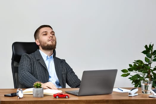 young man sitting on chair at table and resting, using laptop