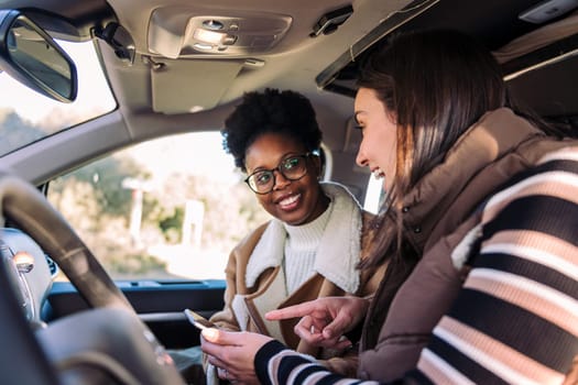 two young women in camper van planning road trip on the phone, concept of adventure and travel with best friend