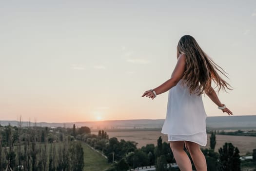 Romantic beautiful bride in white dress posing with sea and mountains in background. Stylish bride standing back on beautiful landscape of sea and mountains on sunset