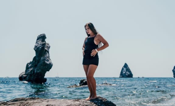 Woman travel sea. Young Happy woman in a long red dress posing on a beach near the sea on background of volcanic rocks, like in Iceland, sharing travel adventure journey