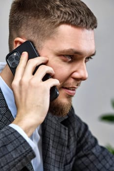 young bearded man in suit talking on mobile phone, close-up