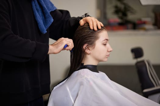male hairdresser is combing the hair of the female client. hairdresser doing hair to his client woman